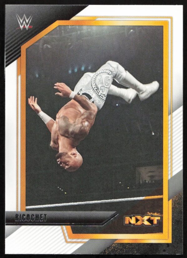 NXT WWE Ricochet executes a stunning mid-air flip in white attire, showcasing his acrobatic prowess.