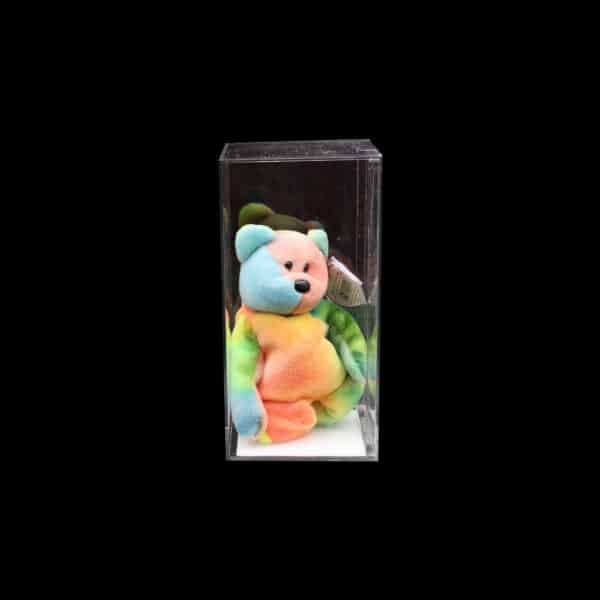 Colorful teddy bear in display case, pastel hues against black, collectible item showcase.